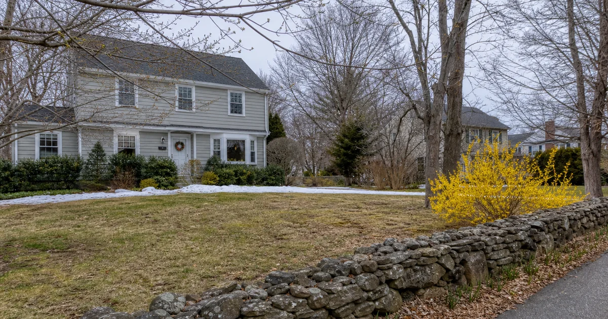 Early spring Connecticut suburban property emerging from winter, with melting snow on lawn edges